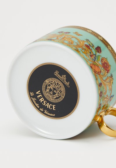 Keramiktasse mit mintgrünem Boden, verziert mit Blumenmotiven und goldenen Akzenten. Verfügt über einen goldenen Henkel und ein schwarzes Markenetikett am Boden.