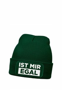 Green knit beanie with a ribbed texture featuring a rectangular patch that reads "IST MIR EGAL" in bold white letters.