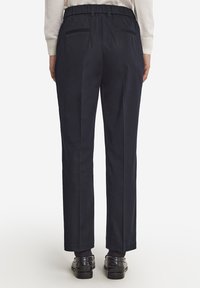 Marina byxor med elastiskt midjeband, med bakfickor. Benen har rak skärning, tillverkade av ett slätt tyg med en subtil lyster.