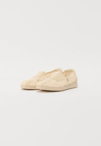 Beige pitskarit kengät, joissa on teksturoitu pinta, kumipohja vaaleassa värissä ja minimalistinen muotoilu.