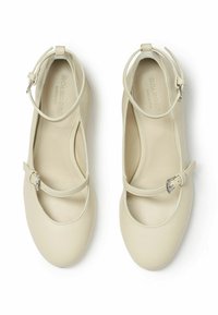 Bailarinas de cuero crema con un strap en el tobillo y detalle de hebilla. Punta redondeada y lados con cortes. Textura suave con costuras mínimas.