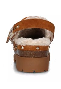 Sandal in suede marrone con una morbida fodera pelosa, una suola spessa e borchie in metallo lungo la cinghia. Fibbia regolabile per adattarsi.