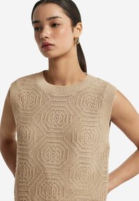 Beige strikket ærmeløs top med et hexagon mønster, ribbet halskant og tekstureret stof, velegnet til varmt vejr.