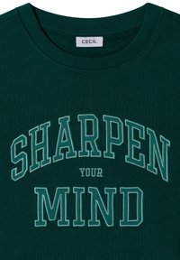 T-shirt vert foncé à col rond avec la phrase "SHARPEN YOUR MIND" brodée en grandes lettres capitales vert clair sur le devant.