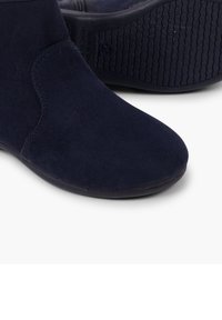 Stivaletti alla caviglia di un blu navy scuro realizzati in suede con una superficie liscia e punta tondeggiante, caratterizzati da una suola in gomma testurizzata per una maggiore aderenza e durata.