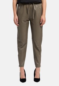 Olivgrüne Kunstleder-Jogginghosen mit elastischem Bund mit Kordelzug, seitlichen Reißverschlusstaschen und schmal zulaufendem Knöchel mit Reißverschlussdetails.
