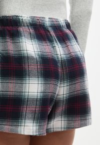 Καρό σορτς που συνδυάζουν ναυτικό μπλε, λευκό και κόκκινο χρώμα, με ελαστική μέση και μαλακό, υφασμάτινο ύφασμα.