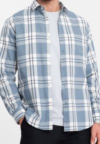 Camisa de cuadros azul y blanca, con cuello estándar, mangas largas y un solo bolsillo en el pecho. Fabricada en tejido ligero.