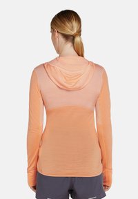 Hoodie orange léger à manches longues avec une texture douce, doté d'une capuche et d'un design arrière semi-transparent.