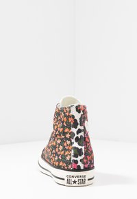 Sneaker alta in tela con un vivace motivo floreale nei toni del nero e del rosa, cuciture bianche e suola a righe bianco e nera.