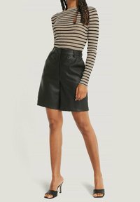 Musta nahkahame, jossa on jämäkkä muotoilu, edessä oleva laskos ja korkea vyötärö. Yhdistetty ruskea ja musta raidallinen ribbipaita.