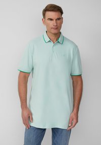 Lichte mintgroene polo met een klassieke kraag, groene accentrand en korte mouwen. Zachte textuur, subtiele logo op de borst.