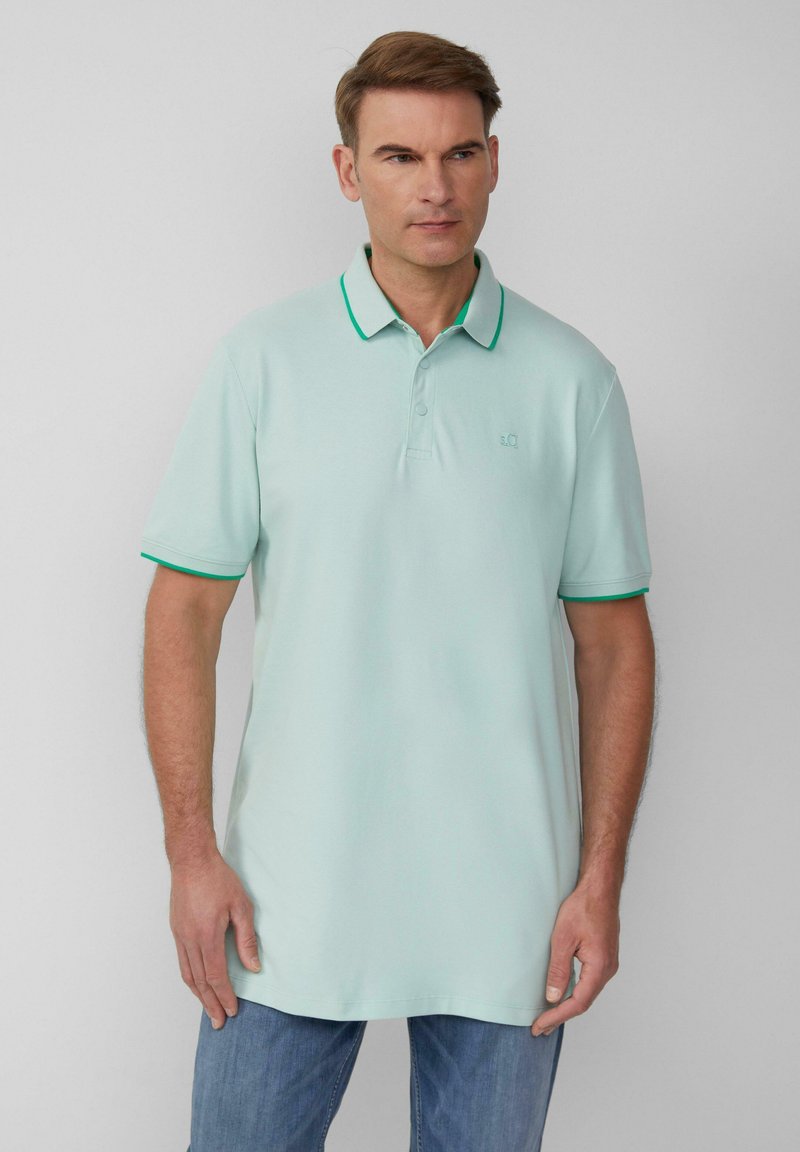 Lichte mintgroene polo met een klassieke kraag, groene accentrand en korte mouwen. Zachte textuur, subtiele logo op de borst.