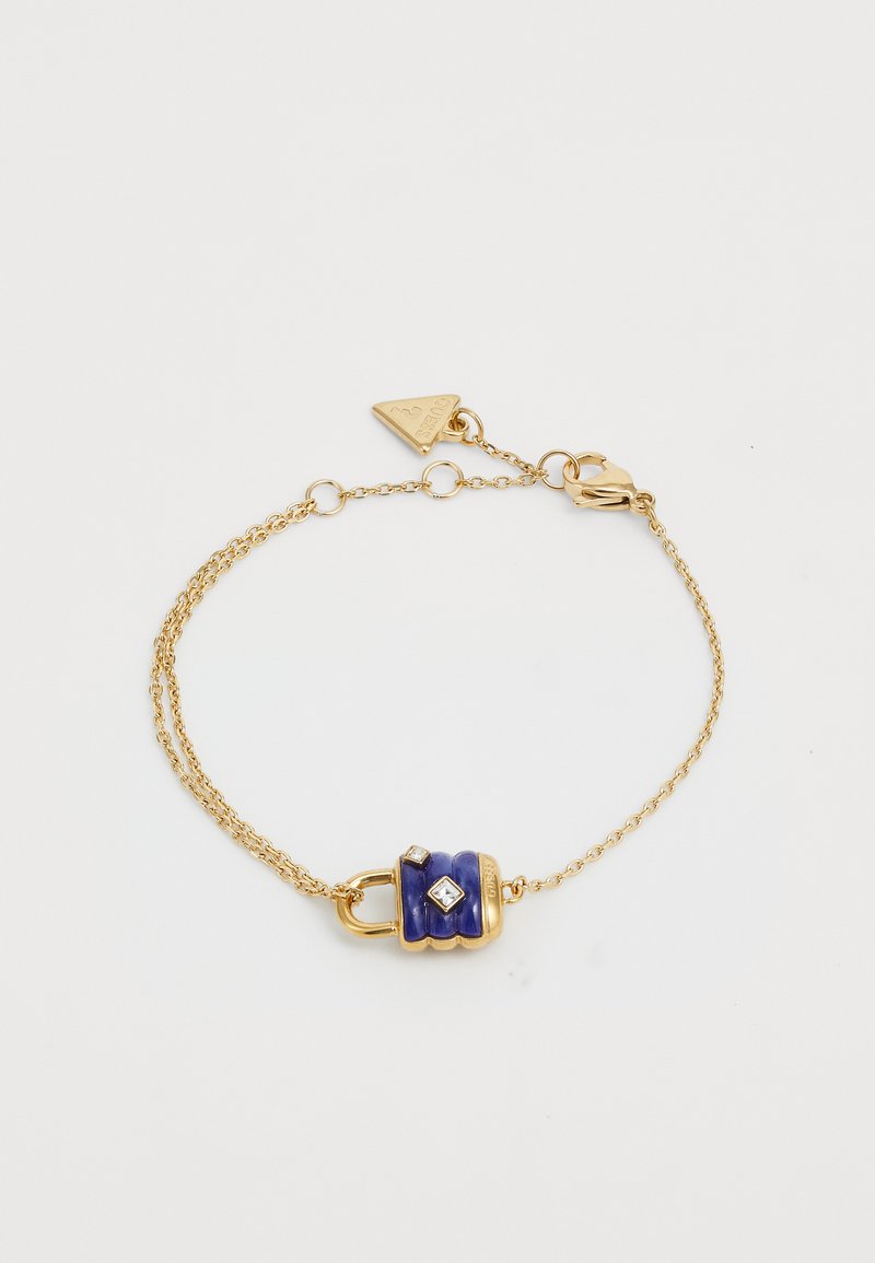 Bracelet en chaîne dorée avec un charme en émail bleu, deux accents en faux diamants transparents et une étiquette triangulaire.