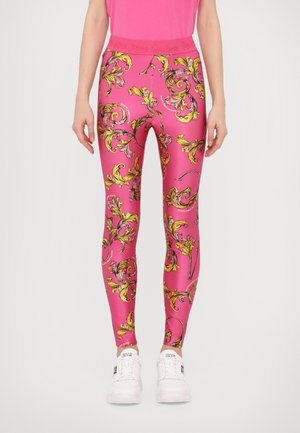 Leggings rosa realizzati in tessuto elasticizzato, con un elaborato motivo floreale giallo e nero, una vita alta e sneaker bianche da attivit sportiva.