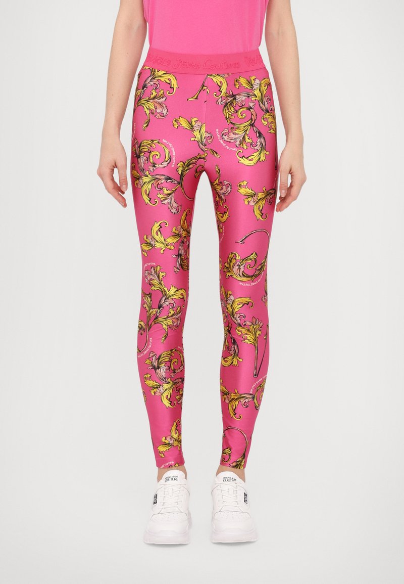 Leggings rosa realizzati in tessuto elasticizzato, con un elaborato motivo floreale giallo e nero, una vita alta e sneaker bianche da attivit sportiva.