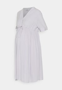 Vestido de maternidade lilás claro com mangas curtas, detalhe de laço na cintura e saia rodada. Feito em tecido suave com acabamento texturizado.