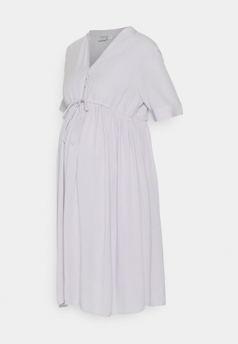 Vestido de maternidade lilás claro com mangas curtas, detalhe de laço na cintura e saia rodada. Feito em tecido suave com acabamento texturizado.