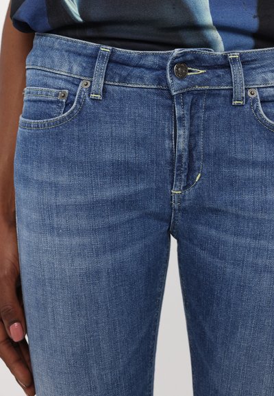 Blå denimjeans med slim fit, mellomhøy midje, fem-f pockets design og kontraststing. Messing detaljer ved livlinjen.