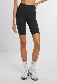 Schwarze, hochgeschnittene Bikerhosen aus einem dehnbaren Stoff. Glatte Textur mit passendem Design, das gerade über das Knie reicht.