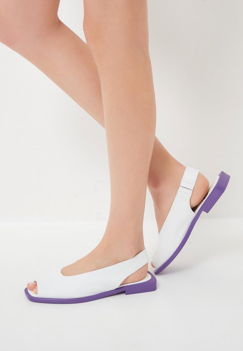 Sandali bianchi open-toe con design slingback. Suola in gomma viola. Texture in pelle liscia con dettagli a intaglio.