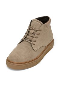 Bottine en suède beige à lacets avec semelle en caoutchouc marron et col rembourré, vue en angle montrant les détails latéraux et supérieurs.