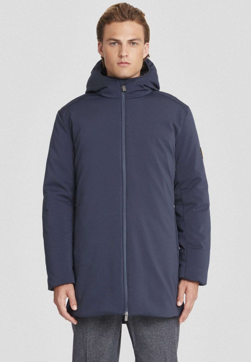 Cappotto imbottito blu navy con colletto alto e cappuccio, dotato di zip centrale e tasche laterali. Texture liscia con silhouette affusolata.