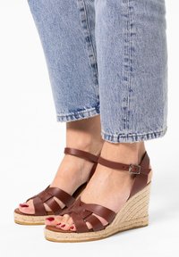 Bruine leren wedge sandalen met een geweven jute platform en enkelbandje, met een kruislings ontwerp in het teengebied.