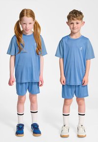Deux enfants portent des tenues sportives assorties de couleur bleu clair, comprenant des t-shirts à manches courtes et des shorts, avec des détails de logo blancs contrastés.