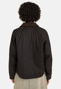 Veste en coton marron avec col en velours côtelé, manches raglan et coupe décontractée. Texture lisse, détails de couture minimes et aucune quincaillerie visible.