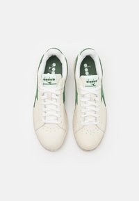 Hvite og grønne lær sneakers med avrundet tå, perforerte detaljer og hvite snørebånd. Har en grønn indre fôr og logo.