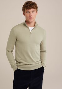 Šviesiai žalia zip-up megztinis su ilgomis rankovėmis ir reinba krašteliais. Turi ketvirčio ilgio užtrauktuką ir lygų, švelnų paviršių.