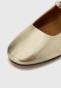 Balerini aurii din piele texturată, cu vârf pătrat și interior neted. Talpa neagră și detalii de design minimaliste sunt prezente.