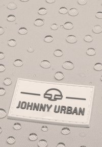 A világosszürke, vízálló anyagon több világos vízcsepp található. Egy fehér címke olvashatóan a "JOHNNY URBAN" felirattal van jelen.