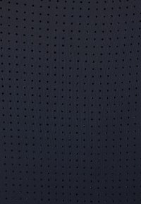 Tissu bleu foncé avec de petites perforations circulaires uniformément espacées, disposées en motif de grille régulière.