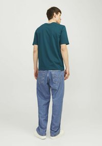 Turquoise katoen t-shirt met een ronde hals, gecombineerd met lichtblauwe denim jeans. Het shirt heeft korte mouwen en een relaxte pasvorm. Eenvoudig ontwerp.