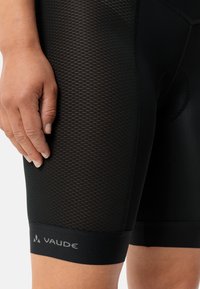 Shorts da ciclismo neri realizzati in tessuto elasticizzato con pannelli in rete. Caratterizzati da cuciture piatte e un logo sull'orlo inferiore. Dettaglio di design testurizzato.