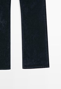 Pantaloni in denim blu scuro con una texture liscia, gambe dritte e sfumature sottili, con una cintura standard e orli rifiniti.