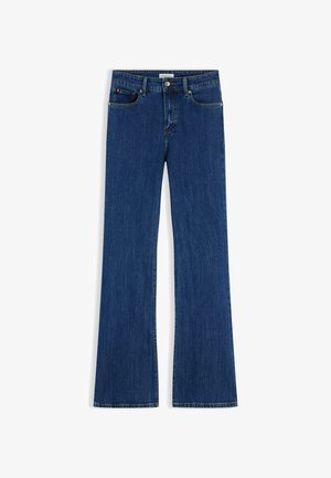 Jean bootcut en denim bleu foncé avec fermeture à boutons devant et fermeture éclair, cinq poches et détails de couture visibles.