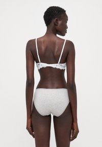 Lichte witte bralette met dunne bandjes, gecombineerd met grijze katoenen onderbroek. De bralette heeft een fijne kantverwerking langs de randen.
