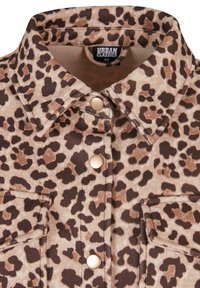 Chemise imprimé léopard avec col pointu, fermeture par boutons-pression et deux poches poitrine cousues, étiquette affichant la marque Urban Classics et la taille XS.
