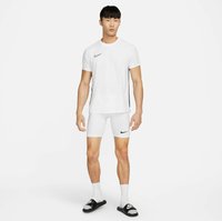 Witte sport t-shirt met zwart Nike-logo, gecombineerd met witte compressie shorts met een zwart logo, witte sokken en zwarte slippers.