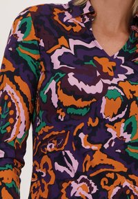 Langsleeve shirt met een kleurrijk bloemenpatroon in tinten paars, oranje, groen en roze, met een V-hals en kraag ontwerp.