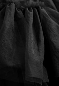 Tissu en tulle noir superposé avec des plis froncés créant un aspect texturé, transparent et volumineux.