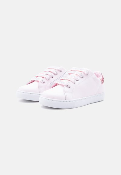 Baskets blanches basses avec des lacets pailletés roses et une doublure en peluche rose, présentées côte à côte sur un fond clair uni.