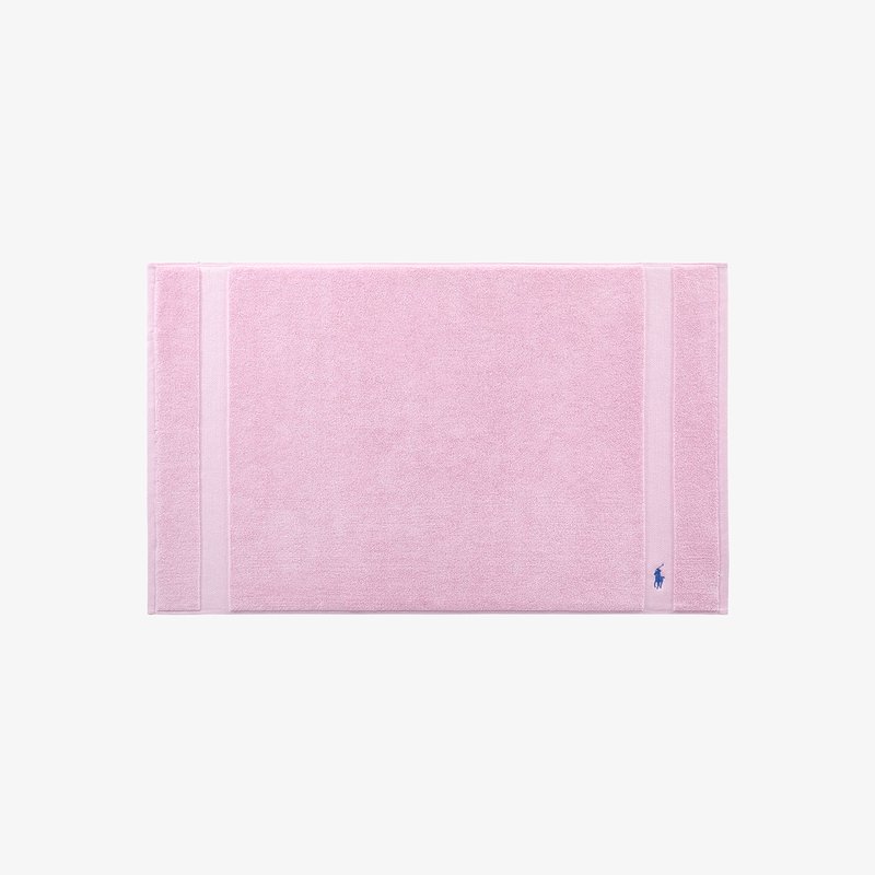 Ροζ χαλάκι μπάνιου με απαλή, υφασμένη επιφάνεια, που διαθέτει δύο οριζόντιες ρίγες και ένα μικρό λογότυπο σε μια γωνία. Ορθογώνιο σχήμα.