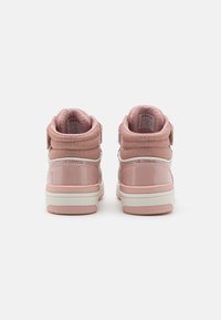 Rozā augsti apavi ar spīdīgu lakādu, teksturētu audumu potītei un Velcro siksniņu. Balti gumijas zoli ar rozā akcentiem.