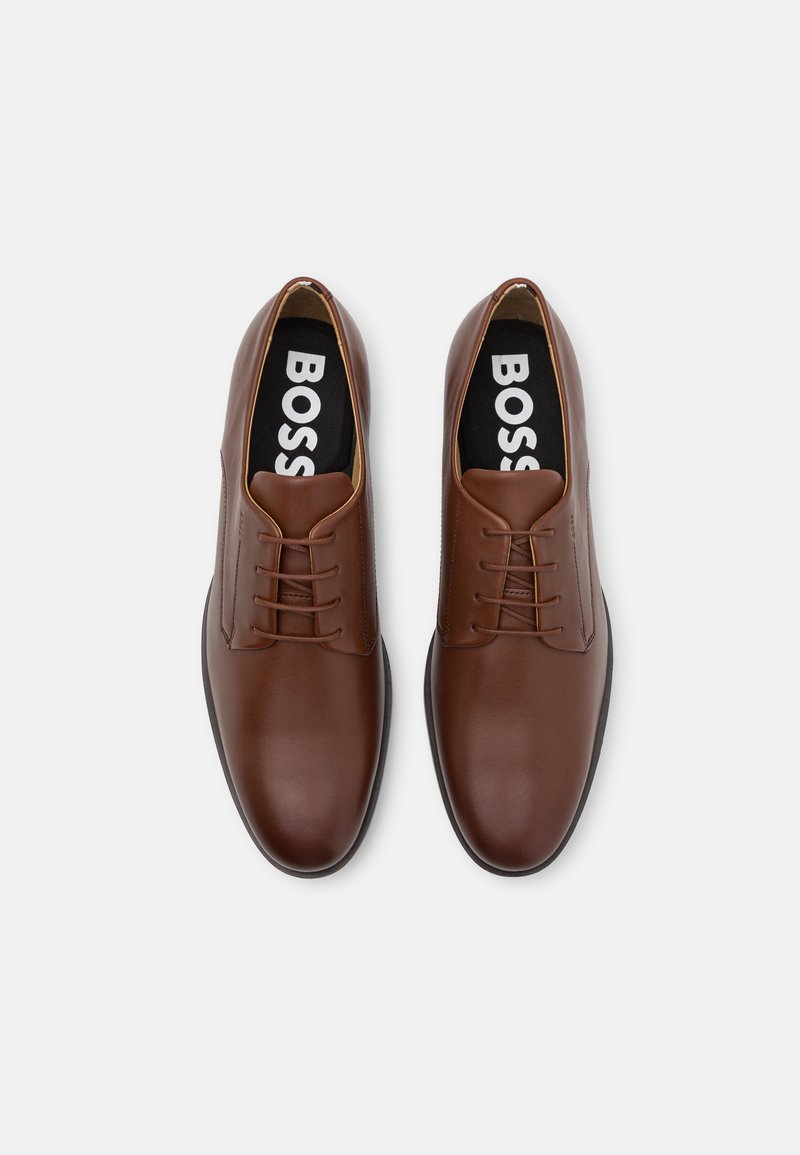 Brown leather shoes with smooth texture, rounded toe, and lace-up design. Inner sole features bold "BOSS" branding in white.