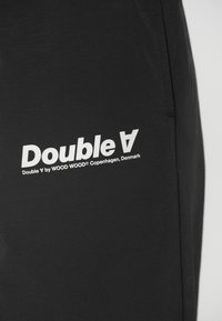 Crne atletske kratke hlače od teksturiranog materijala, s bijelim "Double V" logotipom i brendingom. Jednostavan dizajn bez dodatnih uzoraka ili akcenta.