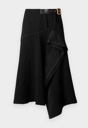 Gonna nera con vita aderente e cintura con fibbia dorata, orlo asimmetrico e borchie dorate lungo la cucitura laterale. Realizzata in tessuto morbido.